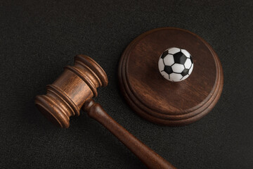 Wooden judge gavel and toy soccer ball. Football coach accused. Concussion lawsuit.
