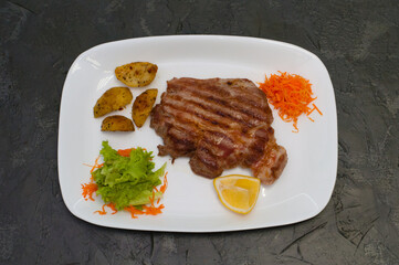 Grilled beef or veal meat steak with lemon, carrots, lettuce and potatoes. Juicy and very tasty dish of Italian cuisine