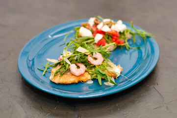 Bruschetta with shrimp, arugula, tomatoes, cheese and sauce, closeup, on gray background, high Italian cuisine