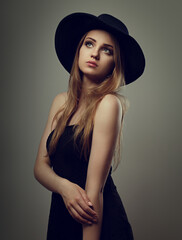 Beautiful makeup woman with long blond hair style in black hat on studio background.. Closeup...
