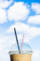 a iced coffee in takeaway cup in the background of blue sky