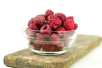 fresh ripe raspberry in a glass transparent bowl on white background
