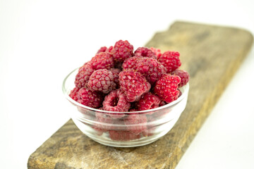 fresh ripe raspberry in a glass transparent bowl on white background