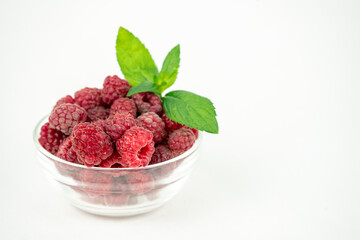 fresh ripe raspberry in a glass transparent bowl on white background