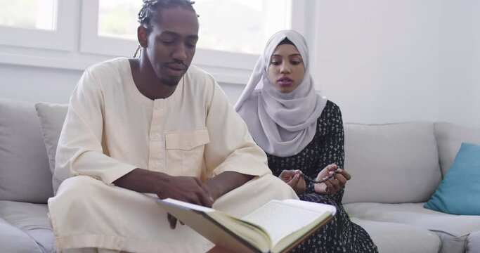 African muslim couple at home in ramadan reading quran holly islam book .