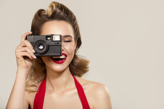 Happy girl in pin-up style holds a retro camera in her hand.