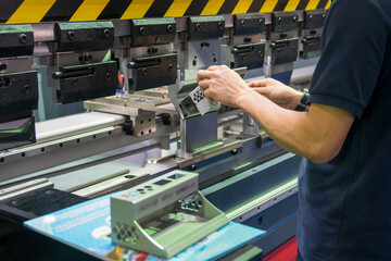 The operation of hydraulic bending machine with technician.  The automotive sheet metal manufacturing process by bending machine with technician operator.
