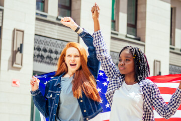 lesbian redhaired ginger woman and her african american wife holding USA flag in downtown street