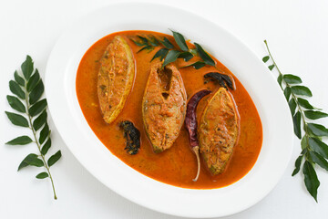 Top view of traditional Goan Pomfret or King fish curry Goa India on dark or black background. Hot and spicy homemade Kerala fish curry yellow curry made using coconut milk , gambooge, turmeric. 