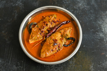 Top view of traditional Goan Pomfret or King fish curry Goa India on dark or black background. Hot...