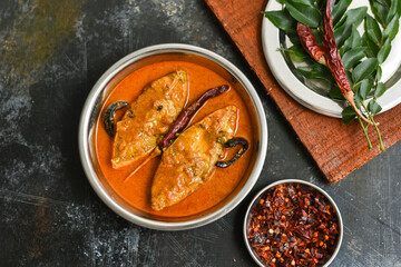 Top view of traditional Goan Pomfret or King fish curry Goa India on dark or black background. Hot and spicy homemade Kerala fish curry yellow curry made using coconut milk , gambooge, turmeric. 