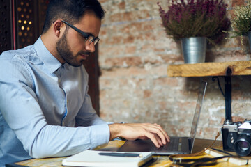 Skilled male copywriter concentrated on completing working task making distance job in cozy cafe...