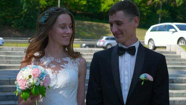 Bride and Groom Walk in Park Looking at Each Other. Urban Scene. Slow motion