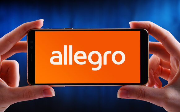 Hands holding smartphone displaying logo of Allegro