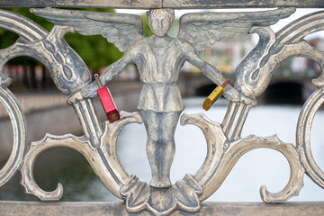 Locks of lovers attached to an angel figure in a bridge