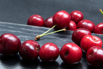Frisch gepflückte rote Kirschen vor schwarzem Hintergrund als Studioaufnahme.
