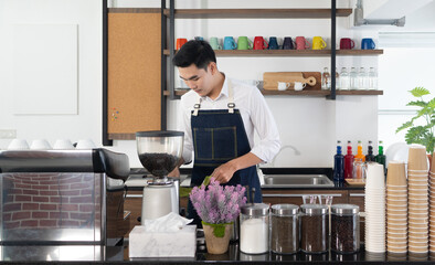 young asian man using coffee maker to brew expresso in the cafe. barista and coffee shop concept