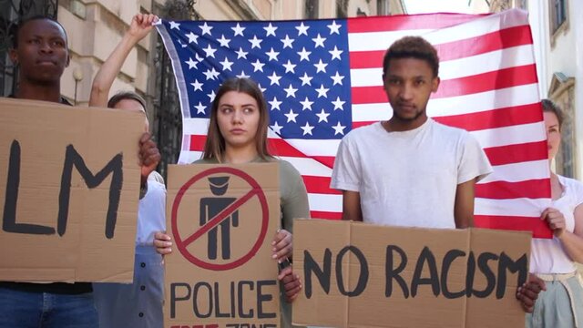 Young students of different skin colors protest against racism and violence against the backdrop of the us flag