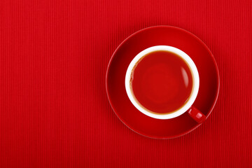 Cup of black tea on red saucer