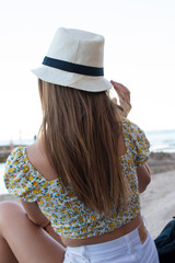 Pretty girl form the back with hat on the beach