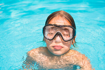 Naklejka premium Pretty young girl in the water, portrait of kid with diving mask in swimming pool