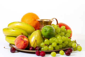 Assortment of exotic fruits on a tray with a jug with splashes of water on a white background. Healthy lifestyle concept.