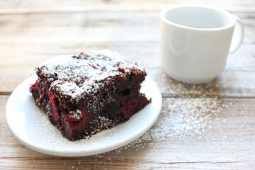 Cup of coffee with handmade chocolate cake on wooden table background. Brownie with cherries on a...