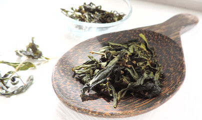     dry green tea leaves   on a wooden spoon            