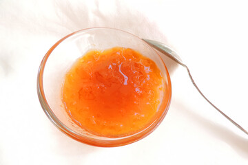     apricot jam in a transparent bowl on a white background 