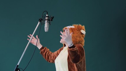 The young adult female with lion costume plays some role during voice over recording. Woman having fun, she is roaring like a lion to the microphone