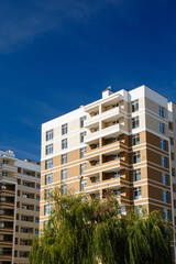 Fototapeta premium New-constructed unfinished multi-storey residential building. multi-storey residential house in brown and beige colors. Modern residential construction. Residential fund. Building on background of sky