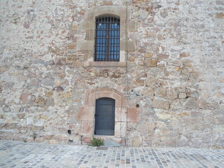 stone wall with wooden windows of the Montjuic Castle, Barcelona, Spain