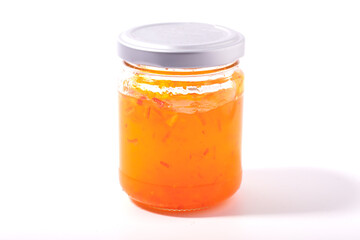Orange jam in a glass bottle on a white background