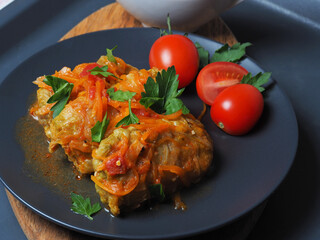 Cabbage rolls with meat, rice and vegetables. Stuffed Peking cabbage leaves with meat, in tomato sauce, on a black plate with tomatoes and herbs. Chow Farchi, dolma, Sarma, cabbage rolls or golabki.