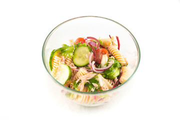 One bowl of salmon pasta salad and a few red tulips flowers in withe background.