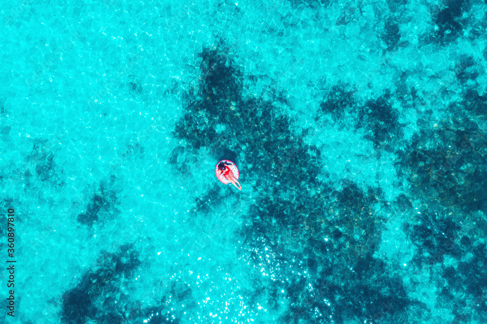 Wall mural girl floating and relaxing in turquoise sea water, aerial top view. caribbean holiday and vacation c