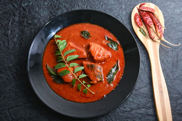 Kerala red fish curry is a hot and spicy seafood cuisine masala gravy Alappuzha India. cooked with ingredients curry leaves, kokkum, coconut milk. Brown rice and fish is popular dish in coastal area.