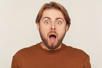 Closeup portrait of surprised bearded man screaming in sudden fright and shock, looking at camera with astonished expression, open mouth in amazement. indoor studio shot isolated on gray background - obrazy, fototapety, plakaty