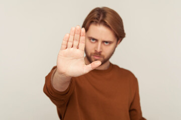 I refuse! Portrait of man with beard in sweatshirt showing definitive no, confident stop gesture and looking with negative expression, warning and declining conflict. indoor studio shot isolated