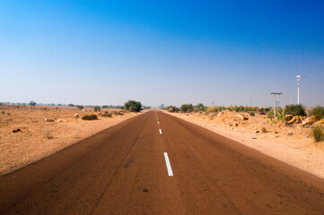 Narrow highway road with barren desert on both sides shot in Rajasthan India