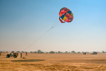 Jeep towing a parachute for adventure para gliding in the empty barren thar desert in rajasthan...