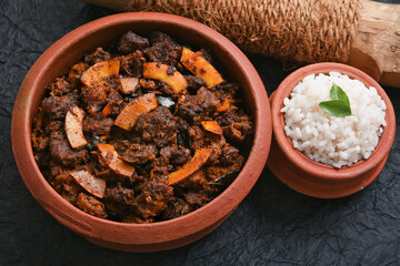 Spicy red beef fry curry and brown rice South Indian dish Kerala, India. side of Ghee rice, Appam, Parotta, Puttu. traditional Christian Muslim feast dish. Buffalo roast, meat pepper fry with coconut.