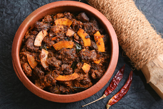 Spicy red beef fry curry and brown rice South Indian dish Kerala, India. side of Ghee rice, Appam, Parotta, Puttu. traditional Christian Muslim feast dish. Buffalo roast, meat pepper fry with coconut.