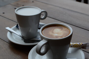 Cups of coffee with milk on a wooden table in a terrace of Gijon.