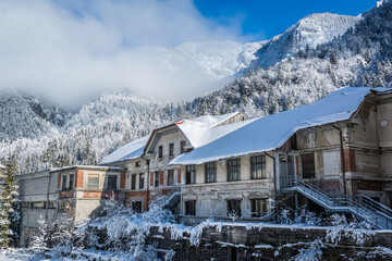 Old abandoned industrial town in Italy. Countryside and Alps mountains covered with snow in wintertime. Cold sunny and bright day