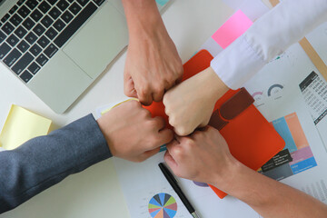 Close up  top view of young business people using fist bump (punching fists or clash of two fists) after complete a deal in the office, fist bump colleagues collaboration, teamwork concept.