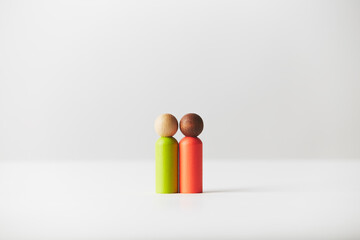 Wooden toy figurines concept. Mixed colour skin couple standing in the middle.   White caucasian person with black African American person. Different race couple, genders or age unknown.