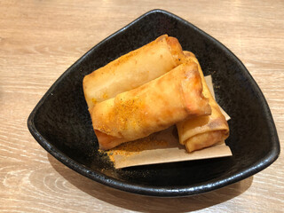 Deep Fried Spring Rolls serving on black plate, classic snack food made with ground pork, matchstick cut carrots, sliced cabbage and thinly sliced onion all wrapped up and fried until golden