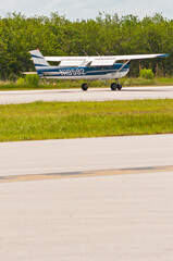 Side view, very far distance of a single prop, private aircraft, landing, on tropical, island airport, in the gulf of Mexico on a sunny afternoon