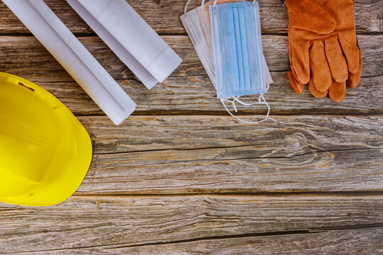 Medical wearing face medical mask for protect coronavirus covid-19 construction office engineer working on blueprints house plans working yellow helmet safety protective gloves